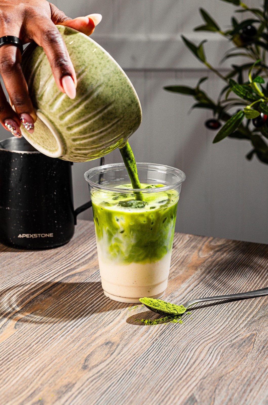Iced matcha latte being hand-poured from a ceramic bowl, studio lit by a Brooklyn food photographer